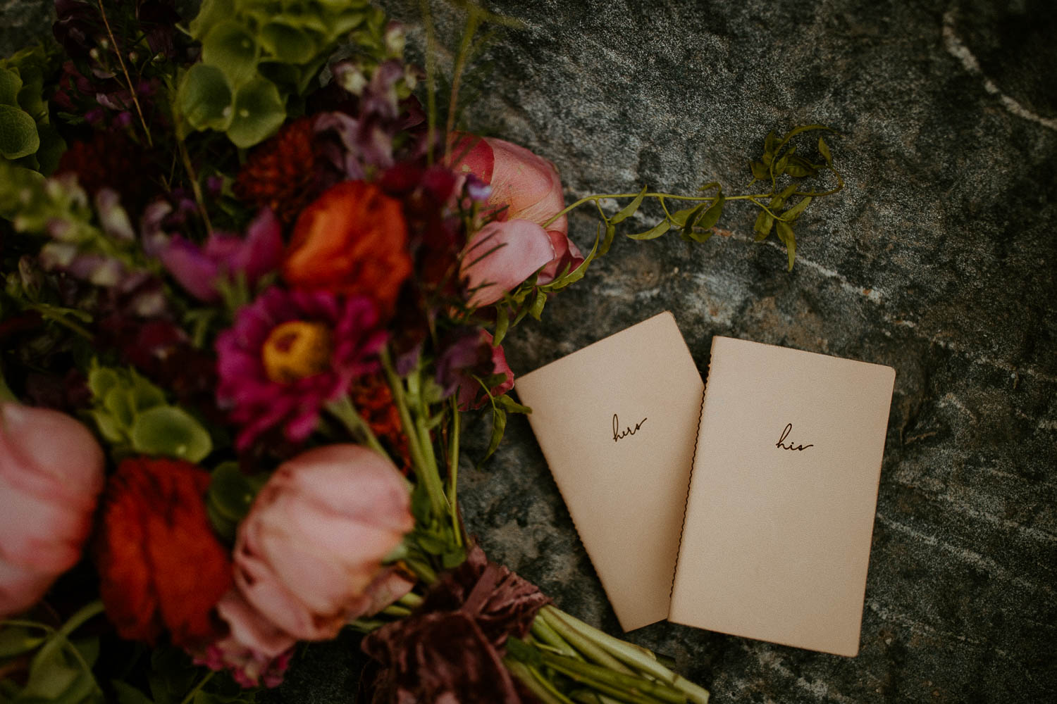Two vow books sitting on a rock next to a vibrant bouquet for a Breckenridge Elopement.