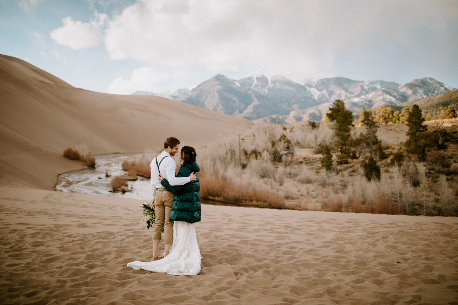 A couple at Great Sand Dunes National Park in Colorado with the Rocky Mountains in the distance.
