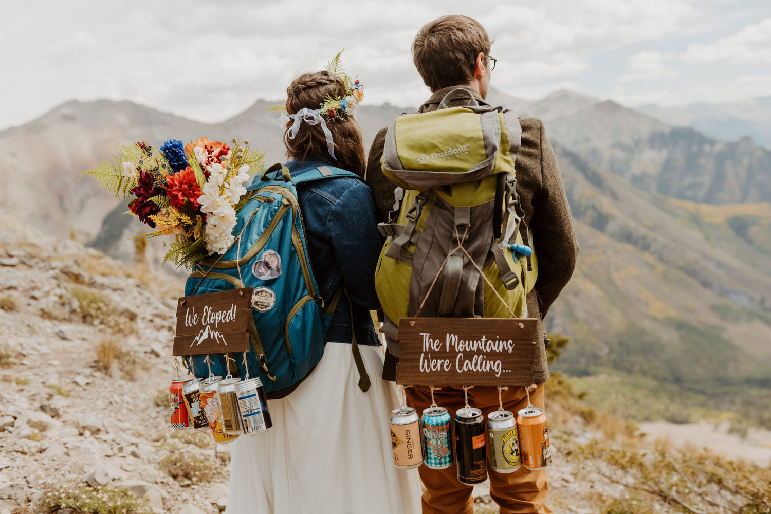 A couple with backpacks on their backs looking out at the mountainscape of the San Juan Mountains in front of them.