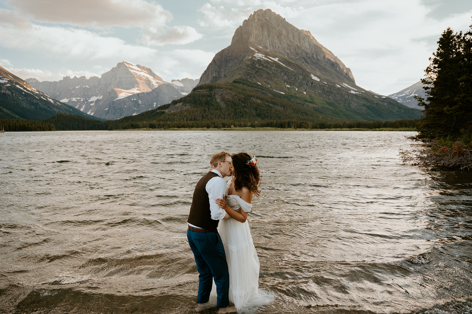 Darcie and Jackson during their intimate elopement in Montana in Glacier National Park in the lake with the beautiful mountains of Many Glacier behind them.