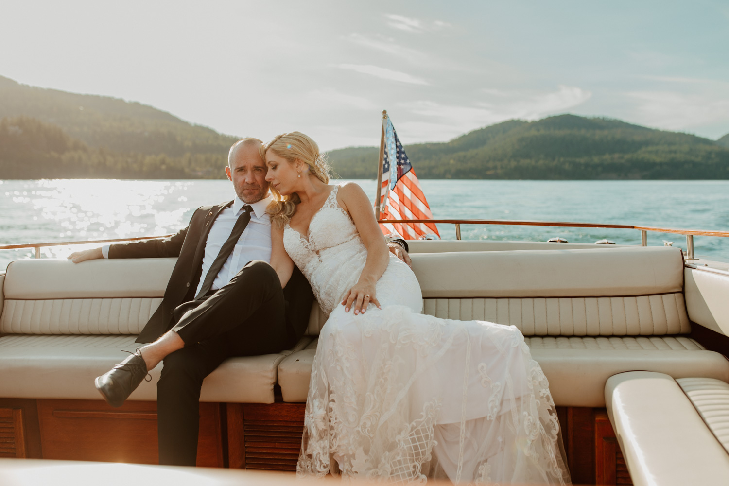 A couple snuggling on the back of a boat during their wedding day at the Lodge at Whitefish Lake.